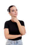 Confident woman in a black top and jeans, wearing bold gold earrings and rings, striking an elegant pose with a thoughtful expression.