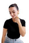 Smiling woman wearing gold hoop earrings and statement rings showcasing elegant jewelry fashion.