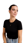 Elegant woman in a black top and denim, wearing gold stud earrings and a delicate gold necklace, exuding modern sophistication.