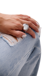 Hand adorned with the Fleur Ring, a standout silver accessory, styled effortlessly with distressed denim fashion.